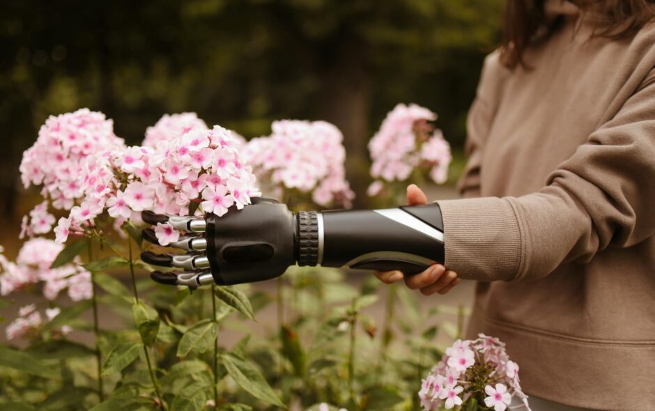 woman touching pink flowers with prosthetic arm